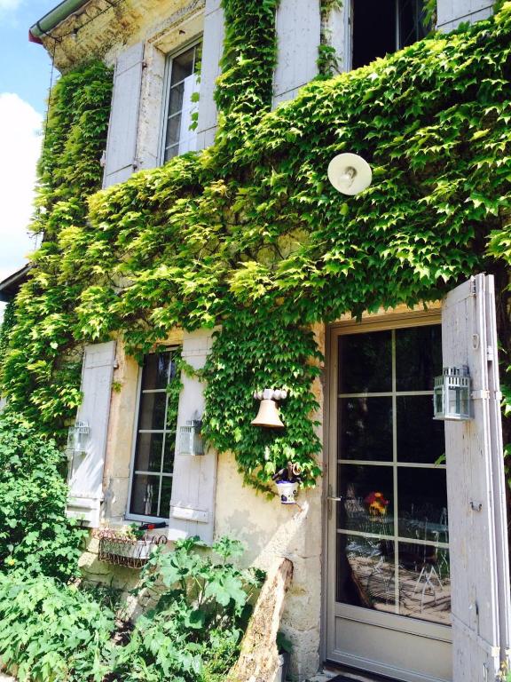an ivy covered building with a door and windows at Chambre d&#39;hôtes Le Moulin de Moulis in Moulis-en-Médoc