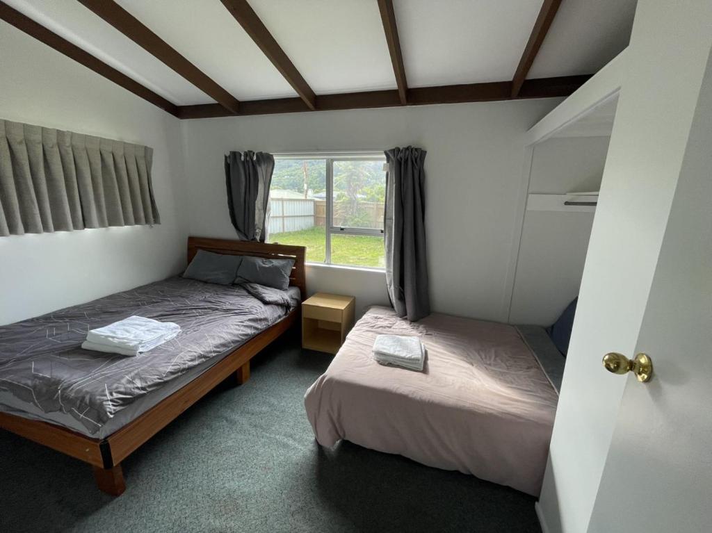 two beds in a room with a window at 3 Bedroom serviced House A, 9 Steeles Lane in Rotorua