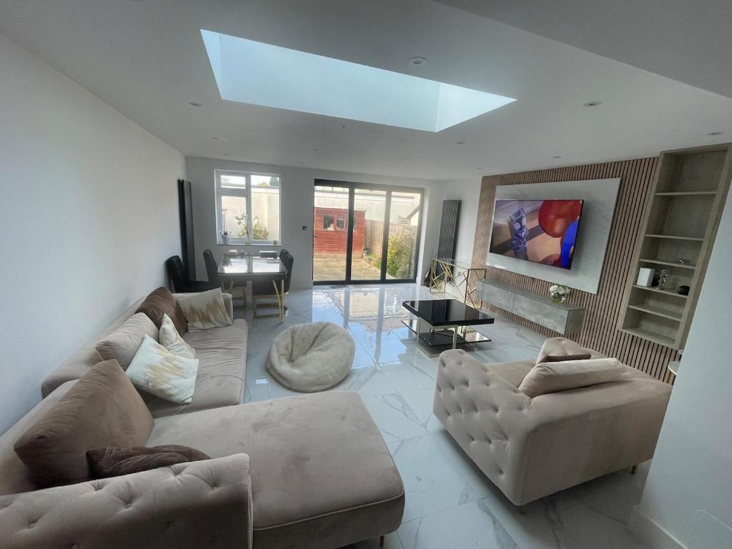 a living room with couches and a skylight at Cosy 4 bedroom house in borehamwood in Borehamwood