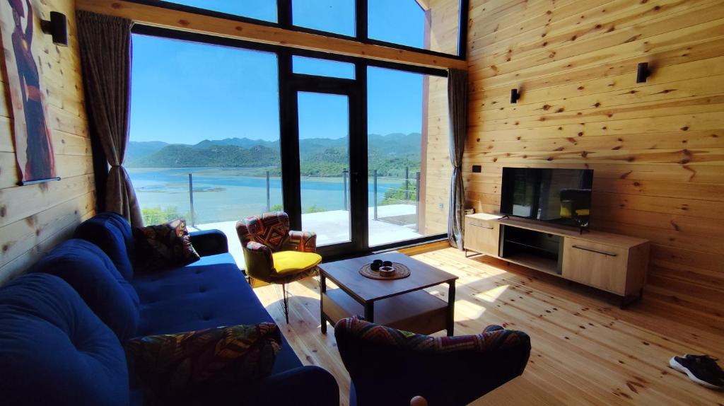 Una sala de estar con un sofá azul y una ventana grande. en Above the Lake, en Rogani