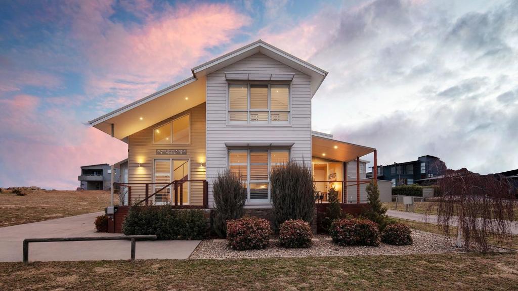 a white house with a sunset in the background at Alpine Snow Angels Retreat in Jindabyne