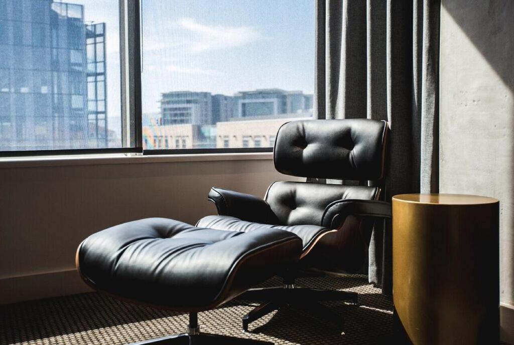 Century City Hotel Urban Square في كيب تاون: كرسي متحرك من الجلد في غرفة مع نافذة