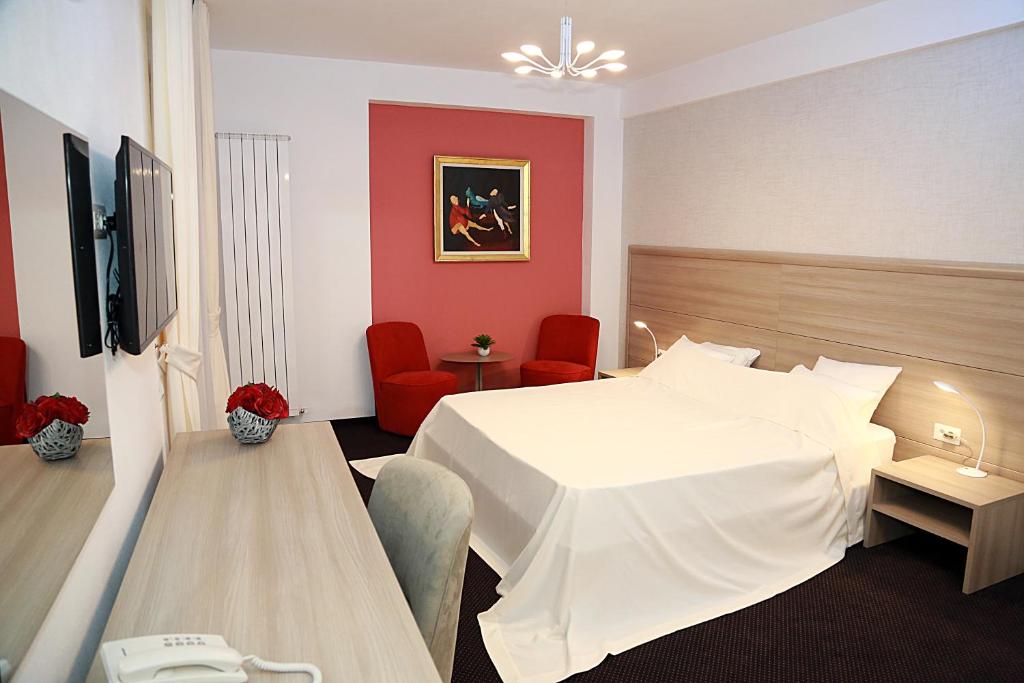 a hotel room with a white bed and red walls at Parliament Square in Bucharest