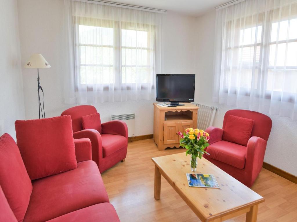a living room with red chairs and a tv at Charming Savoyard Apartment in Giez