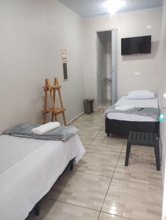 a room with two beds and a tv on the wall at Hotel Tenda São Bernardo do Campo in São Bernardo do Campo