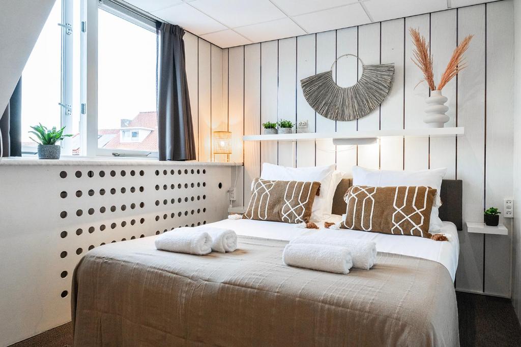 a bedroom with a large bed with two towels on it at Stylish Suite Steps To Shore in Zoutelande