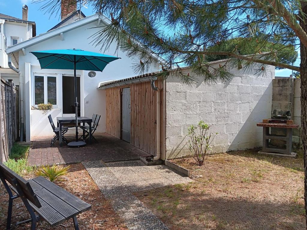 un patio avec une table et un parasol dans l'établissement Maison de Charme Près de la Plage, 5 Pers, Jardin - FR-1-476-232, à La Faute-sur-Mer