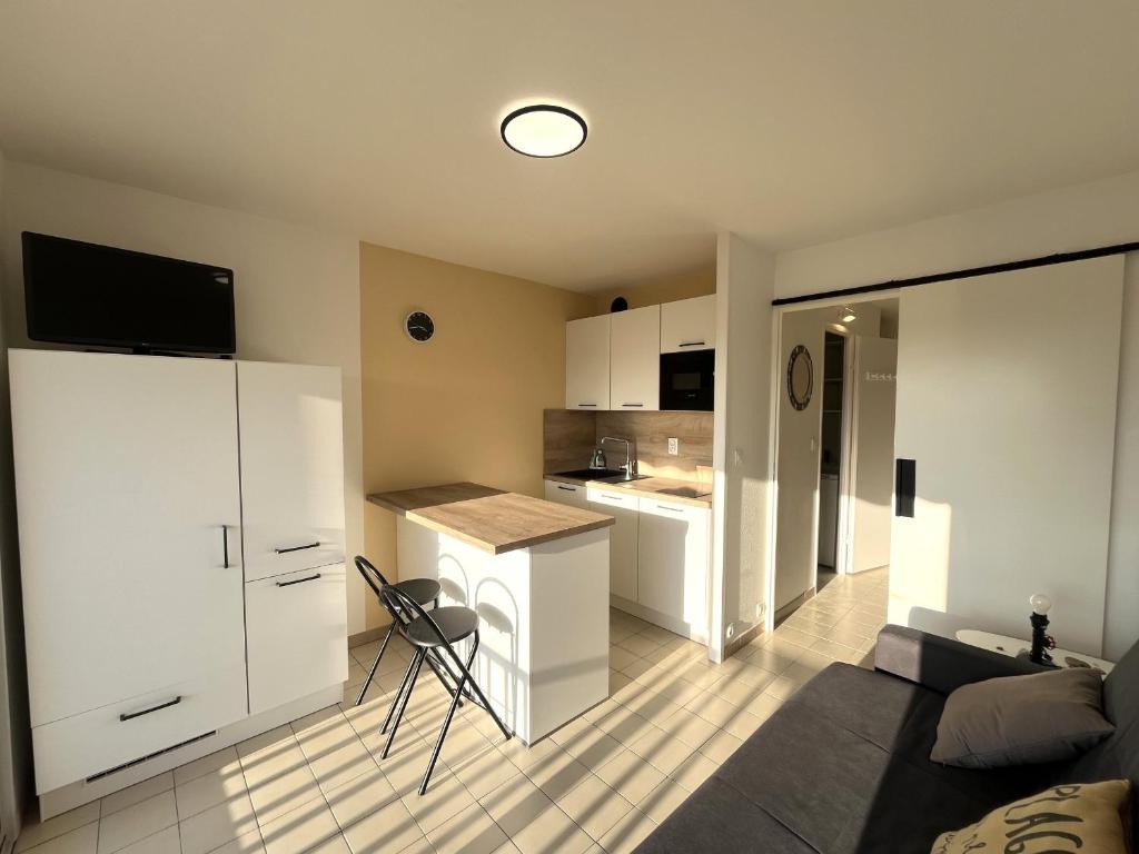 un salon avec un canapé et une cuisine dans l'établissement Studio Cabine Accès Plage - Résidence Sécurisée avec Piscine - FR-1-753-31, à Saint-Cyprien