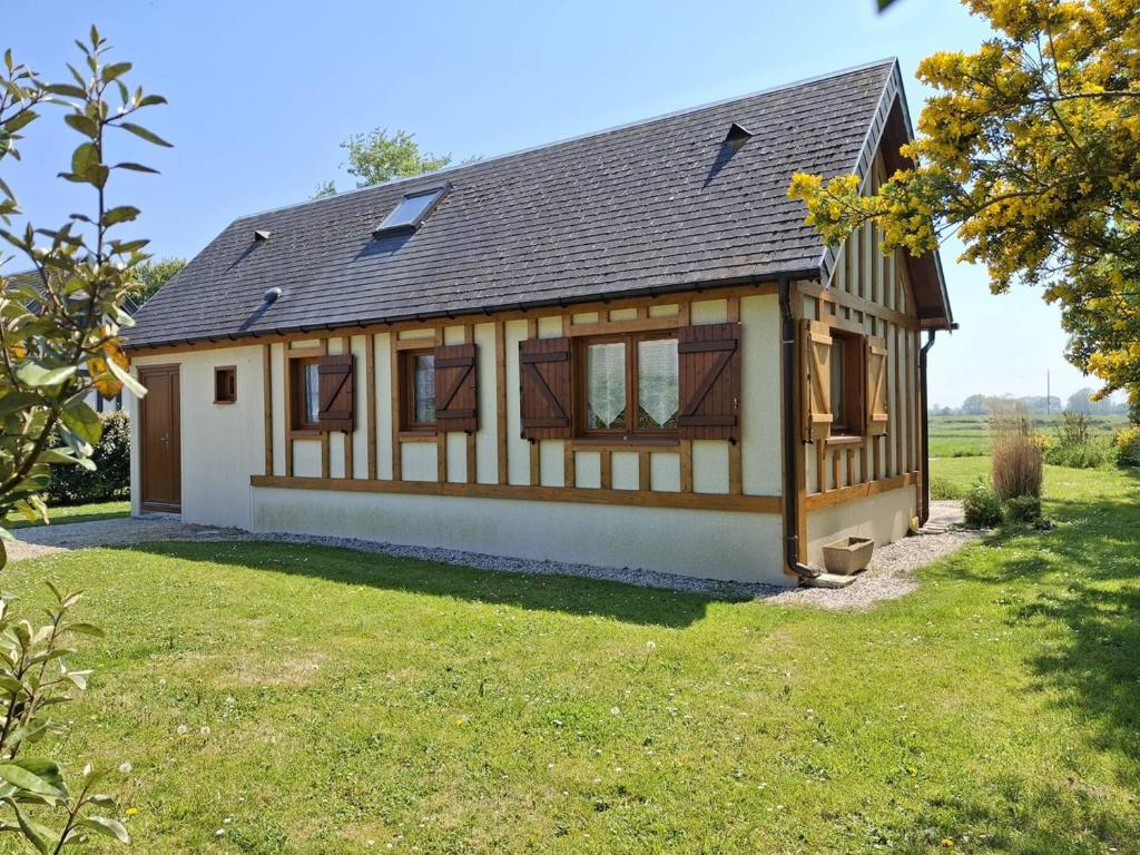 une maison dans un champ avec une cour en herbe dans l'établissement Chalet authentique près de la plage pour 6 personnes - FR-1-788-65, à Merville-Franceville-Plage