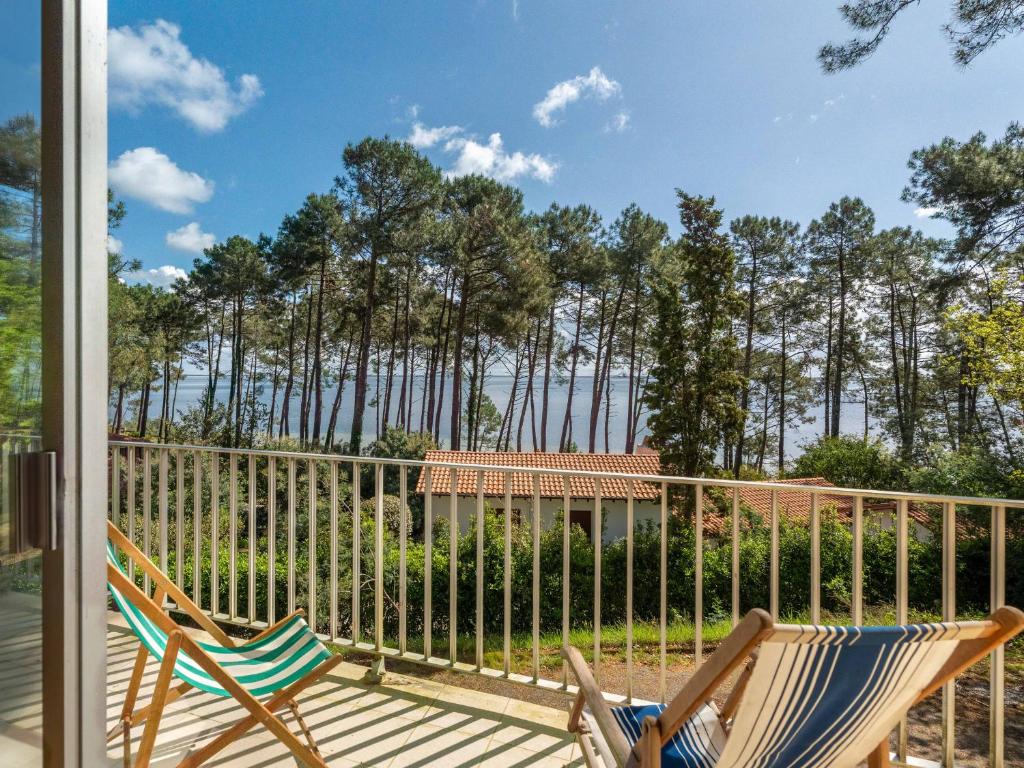 une paire de chaises sur un porche avec une clôture dans l'établissement Grande Villa 14 Pers - Vue Imprenable sur Lac - Tranquillité à Biscarrosse - FR-1-319-605, à Biscarrosse