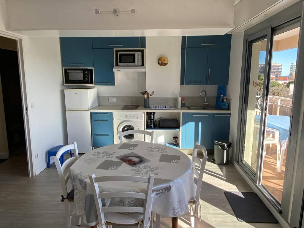 une cuisine avec des armoires bleues et une table et des chaises dans l'établissement Charmant Deux-Pièces Climatisé à Canet-Plage - FR-1-750-87, à Canet