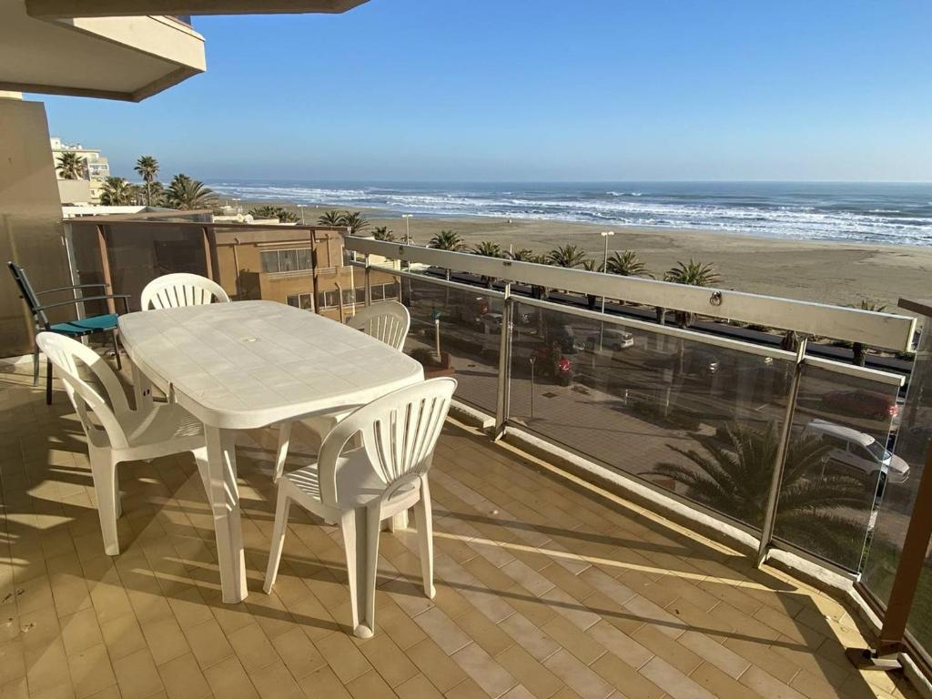 - une table et des chaises blanches sur un balcon donnant sur la plage dans l'établissement Appartement 2 pièces, terrasse face mer, parking - FR-1-750-91, à Canet