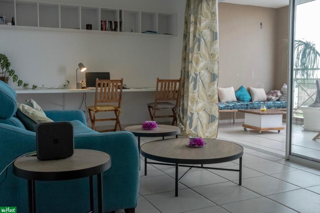 un salon avec un canapé bleu et deux tables dans l'établissement Moutte - Superbe appartement pour deux, à Fort-de-France