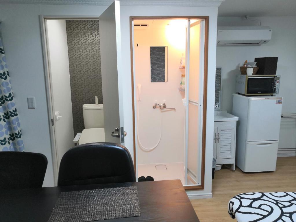 大阪Nippori Osaka Nishi-Tengachaya Guesthouse西天下茶屋アパートメント的一间有门的房间，通向带冰箱的厨房