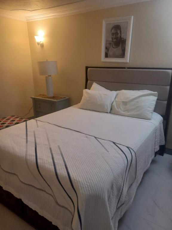 a bedroom with a large bed with white sheets at Finest Accommodation Russell Heights Apt #A in Kingston