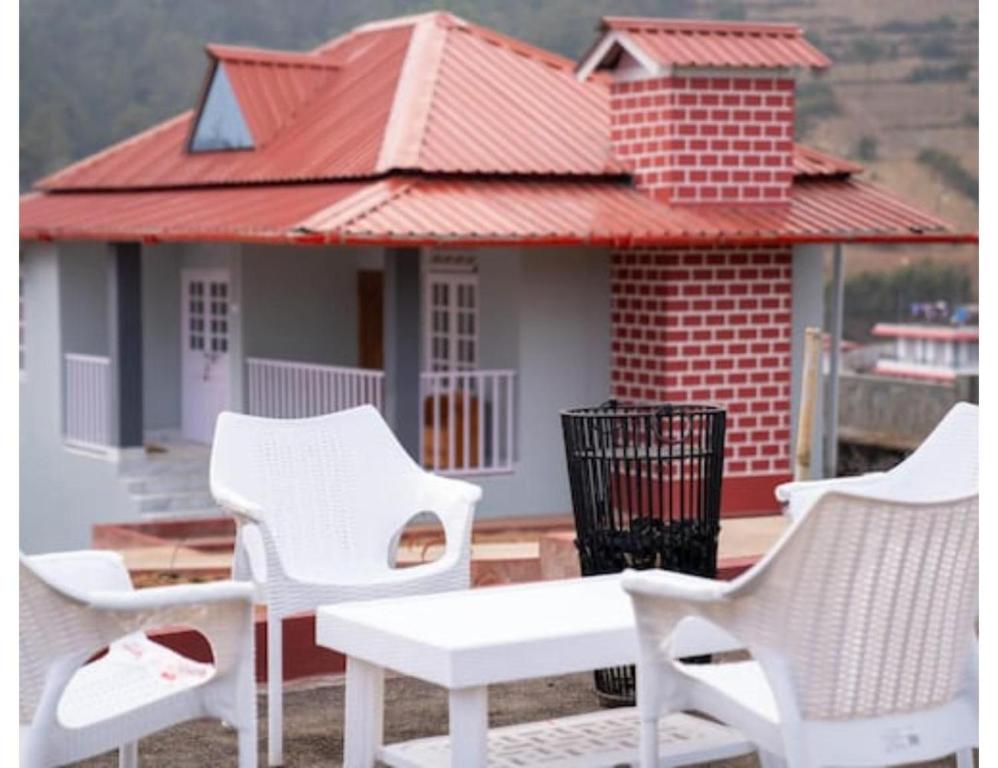 シロンにあるLe Nessa Guest House, Shillongの白い椅子と家の前のテーブル