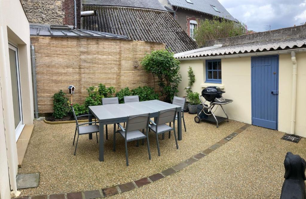 - une table et des chaises dans la cour d'une maison dans l'établissement Maison Familiale de Centre-Ville, à Dives-sur-Mer