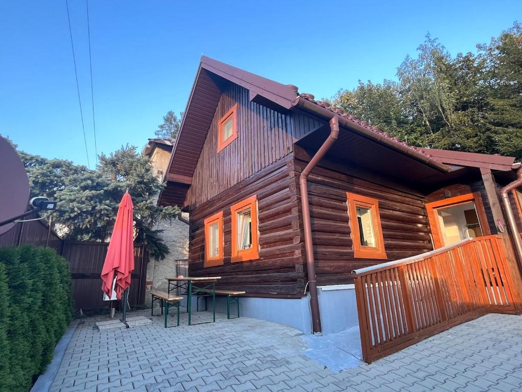 a wooden house with a table and a red umbrella at Drevenica U Feleja in Pohorelá