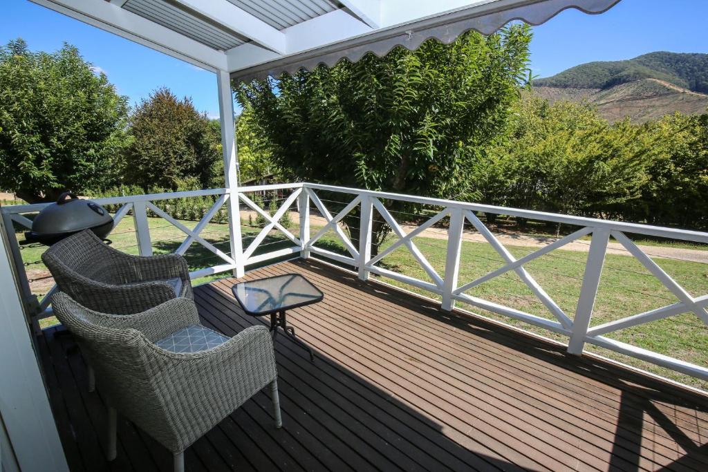 a porch with chairs and a table and a fence at Abby's Cottage - Cosy couples retreat in Wandiligong