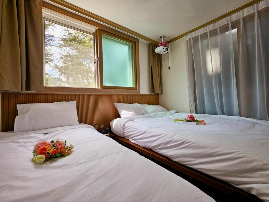 two beds in a room with flowers on them at Gamseong house next to Sung Sim Dang in Daejeon