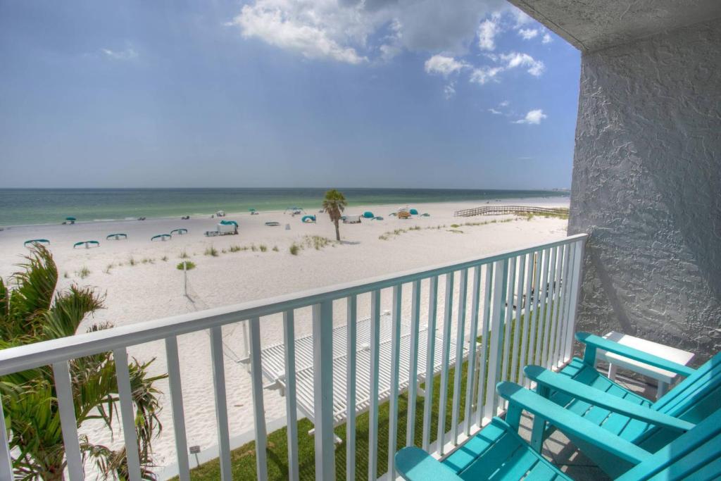 a balcony with chairs and the beach in the background at 318 - Island Inn in St. Pete Beach