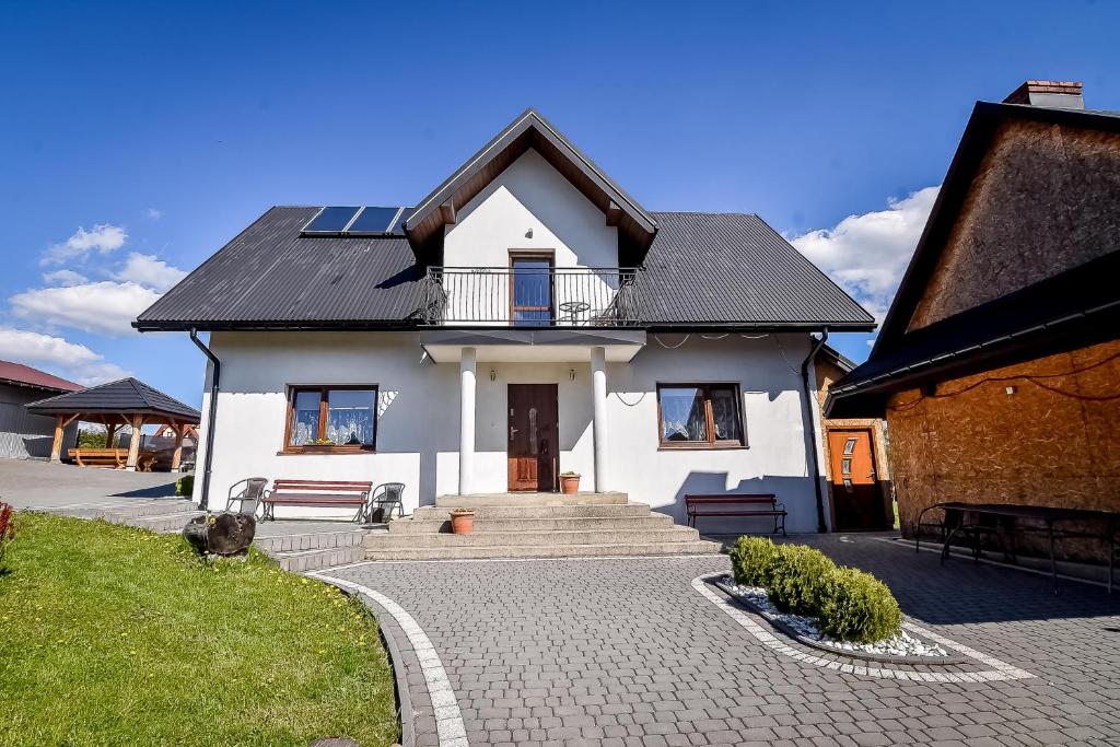 a white house with a black roof and a pathway at Domek Na Brzysku Lipnica Wielka in Lipnica Wielka