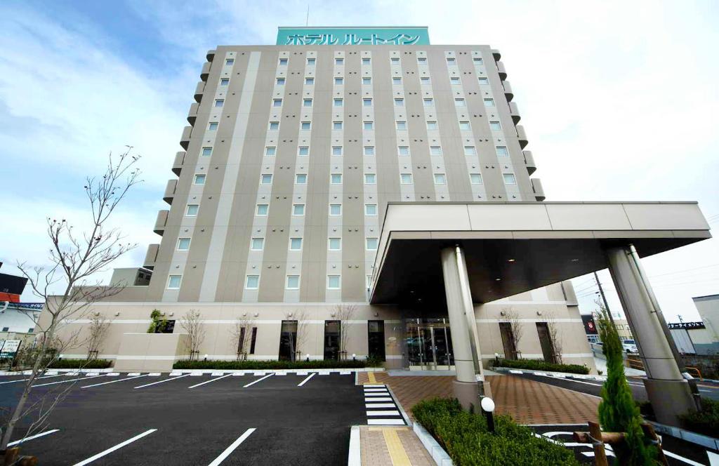 a large building with a parking lot in front of it at Hotel Route-Inn Niigata Nishi Inter in Niigata