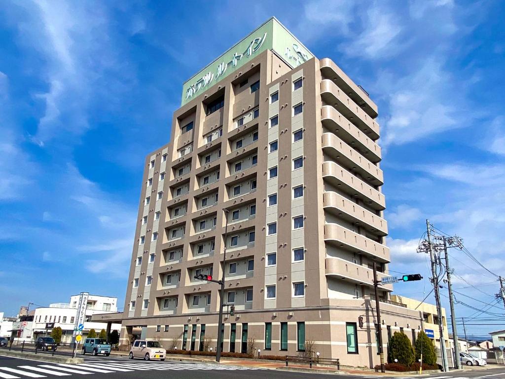 a hotel building with a sign on top of it at Hotel Route-Inn Toyotajinnaka in Toyota