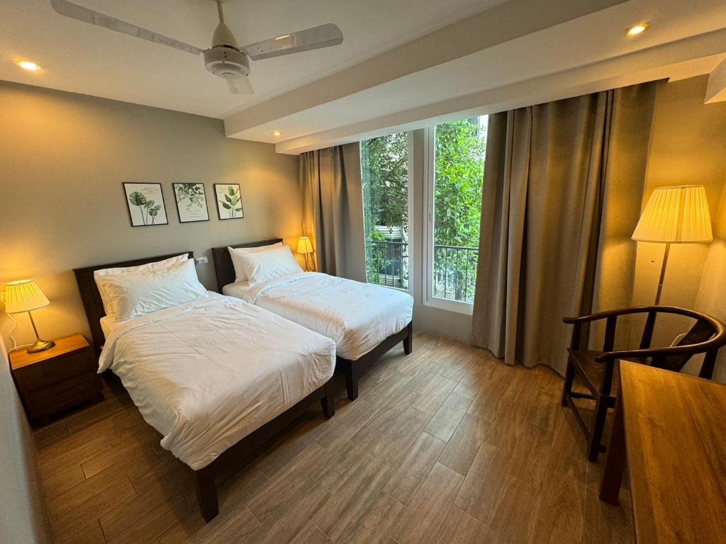a hotel room with two beds and a window at Rimm49 Bangkok in Bangkok