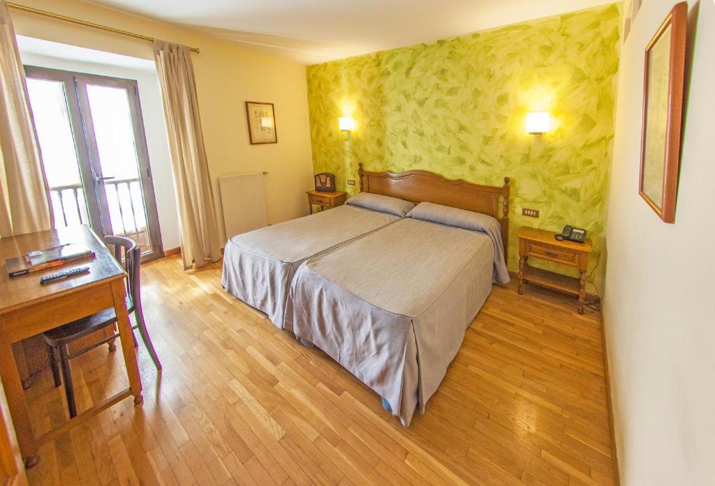 een slaapkamer met een groot bed en een bureau bij La Casona de Jovellanos in Gijón