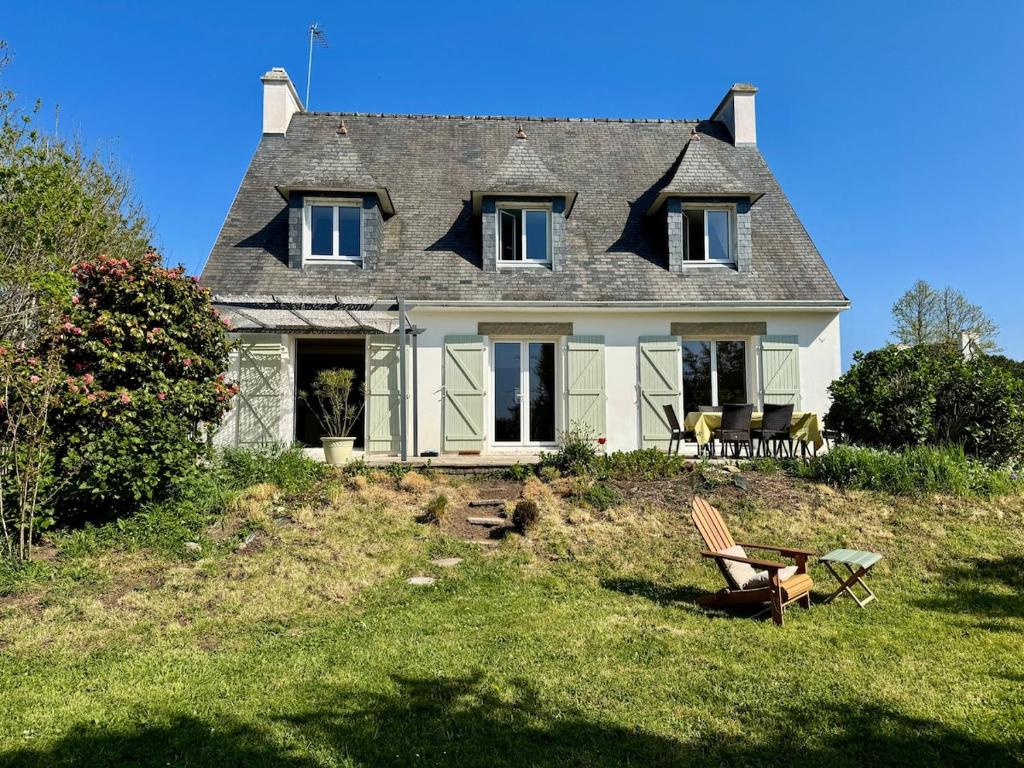 une maison sur une colline avec une chaise dans la cour dans l'établissement Charmante maison près de la plage, Sainte Marine, à Combrit