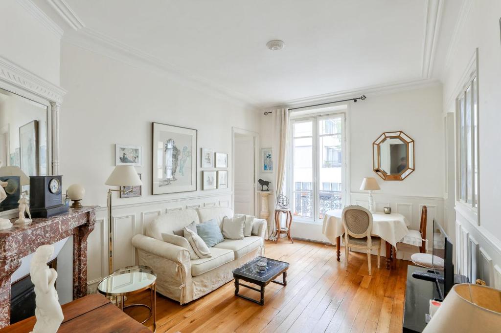 un salon avec un canapé blanc et une cheminée dans l'établissement Stunning Parisian 1BR Flat near Sacré-Cœur, à Paris