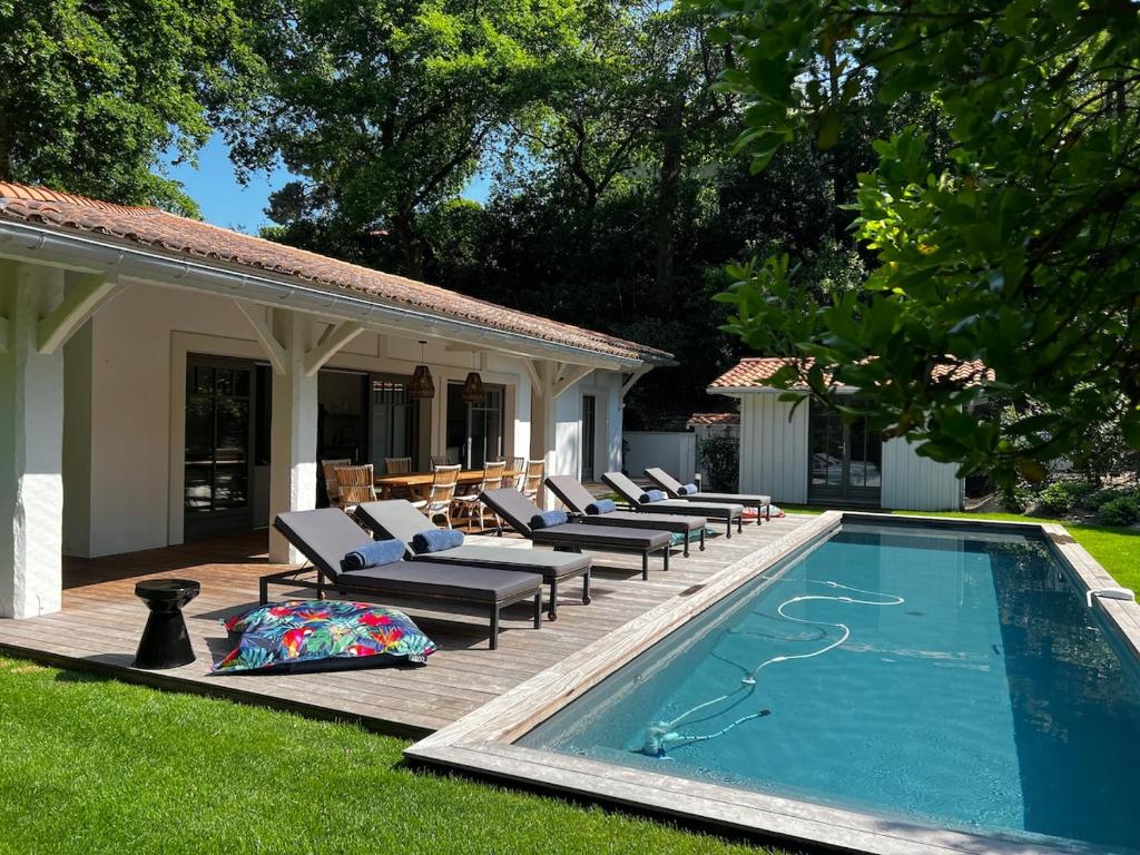 - une piscine avec des chaises longues à côté d'une maison dans l'établissement Villa Romaline - Plage Pereire - Piscine chauffée, à Arcachon