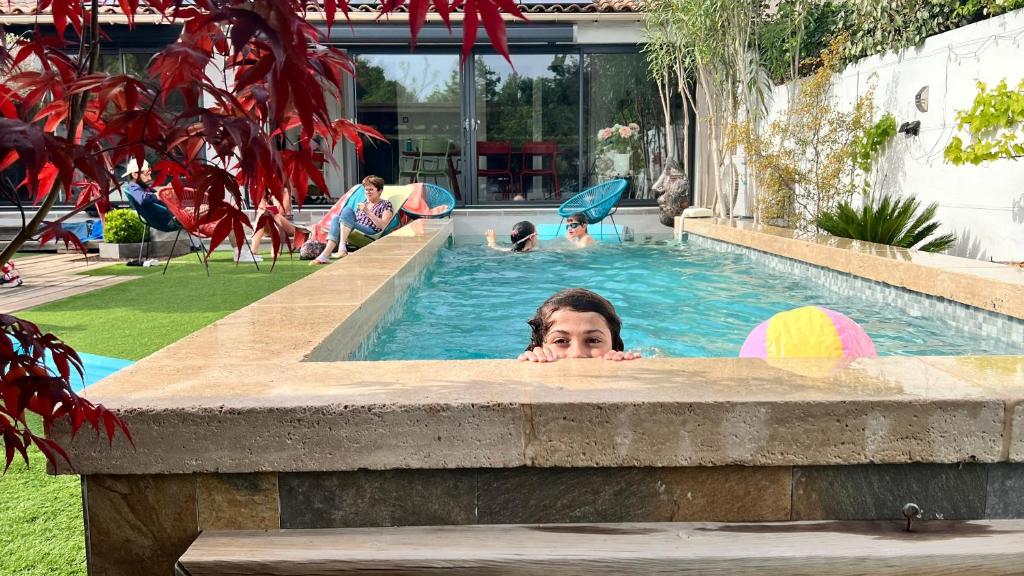 une femme dans une piscine d'un complexe dans l'établissement Très belle maison avec piscine , proche centre ville - Aix en Provence, à Aix-en-Provence