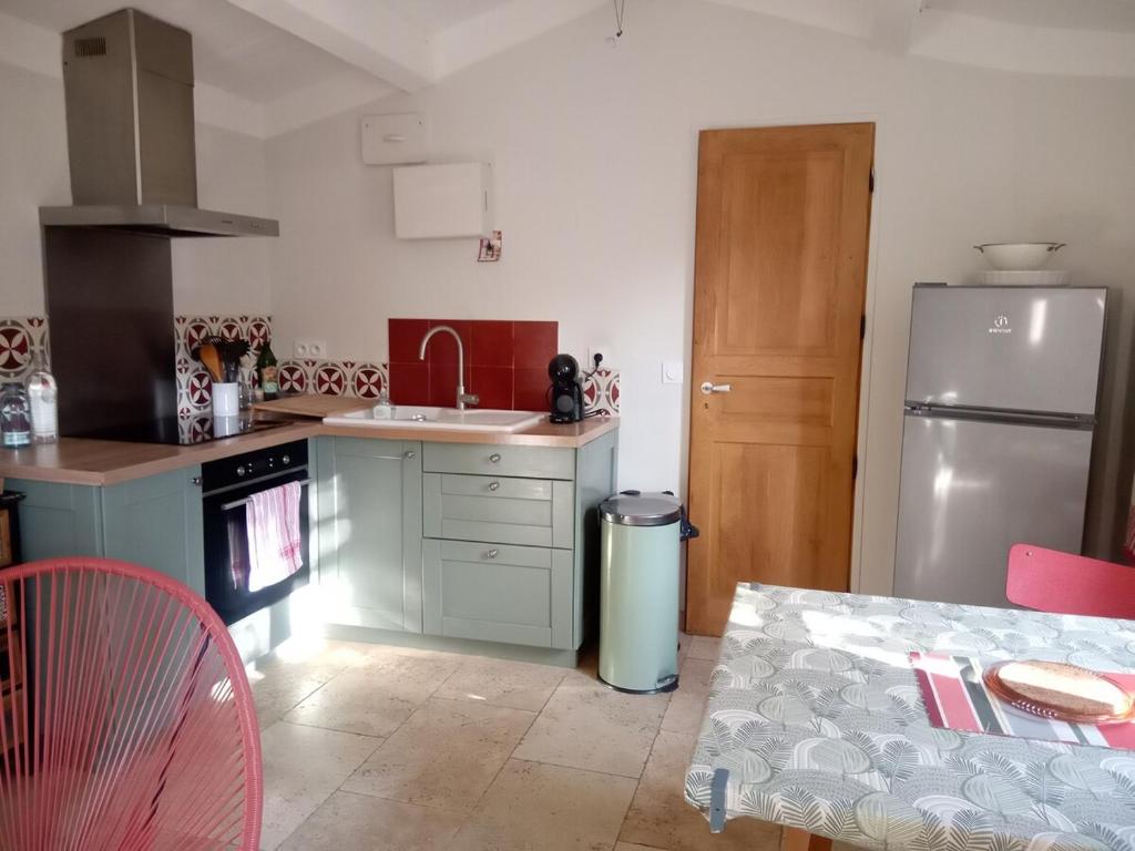 une cuisine avec un réfrigérateur en acier inoxydable et une table dans l'établissement Mazet terrasse et jardin Nîmes, à Nîmes