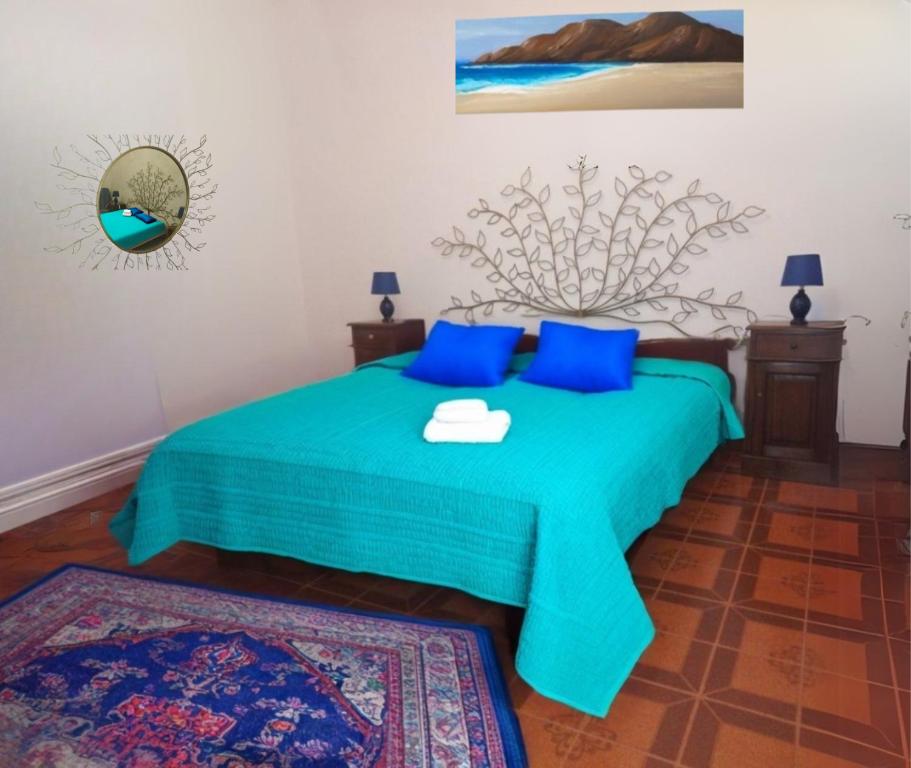 a bedroom with a green bed with blue pillows at Casa Platamone 2 in San Vito lo Capo
