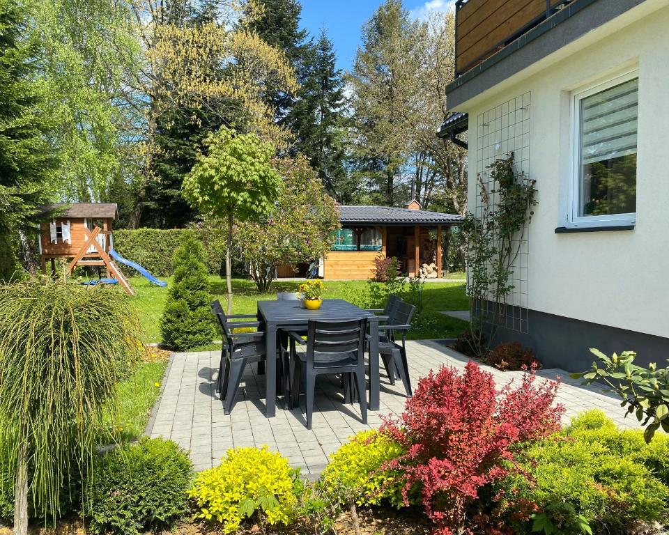 a patio with a black table and chairs in a yard at Apartamenty Fredry in Lesko