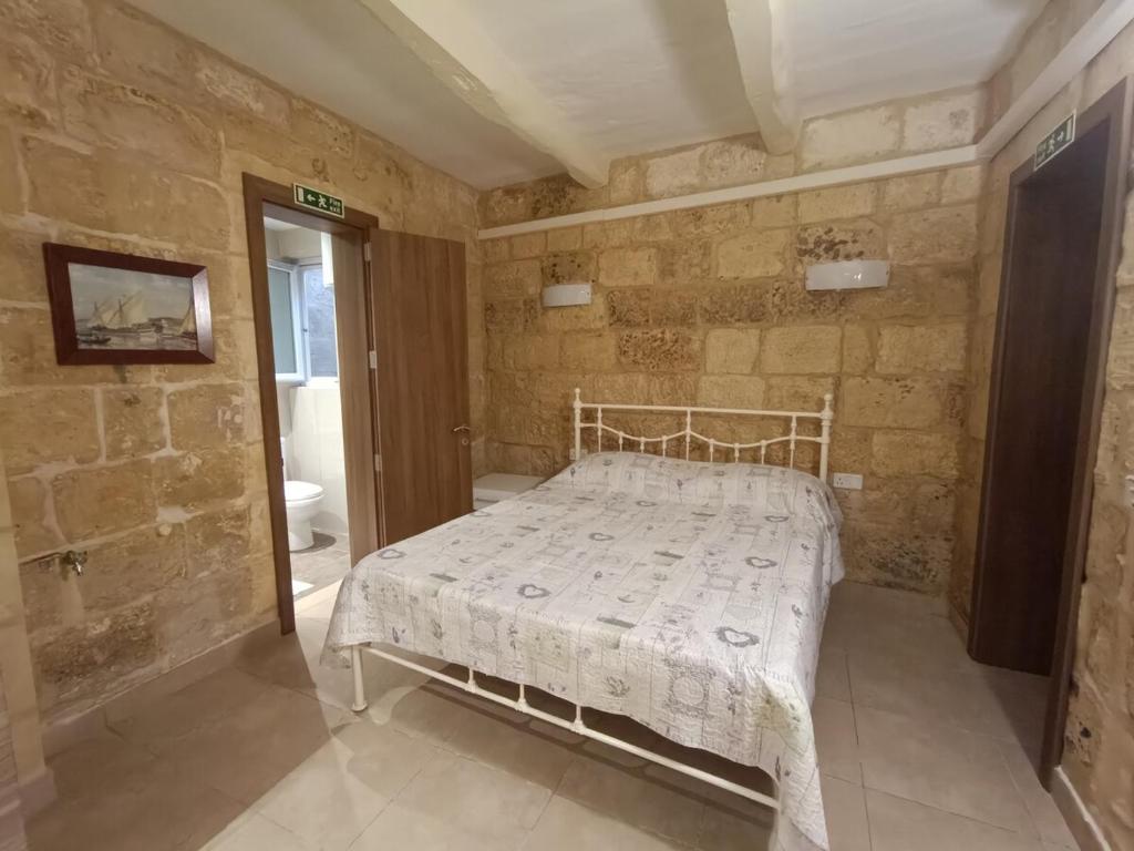 KalkaraにあるKalkara Maisonette in the Alleyの石の壁の中にベッドが置かれた寝室