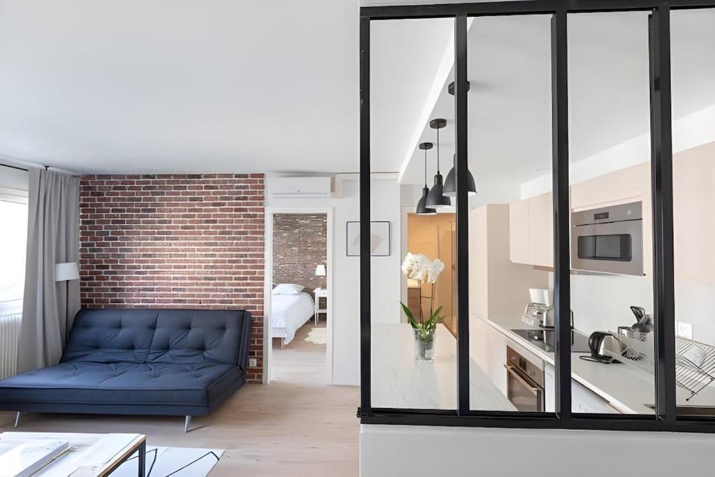 - un salon avec un canapé bleu et un mur en briques dans l'établissement Paris 15 Tour-Eiffel Bd Grenelle - 2 rooms, à Paris