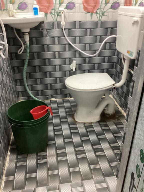 a bathroom with a toilet and a sink and a bucket at Shivay Guest house in Jasidih