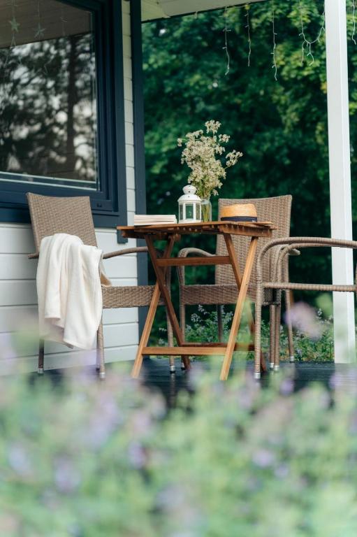 Outdoor seating area with wicker chairs and table, surrounded by greenery.