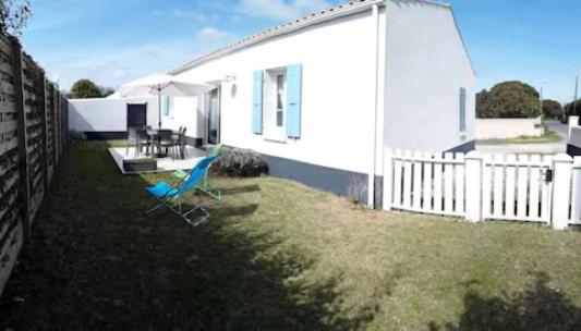 une maison blanche avec deux chaises et un parasol dans l'établissement Maisons à 200 m de la plage, à Saint-Pierre-dʼOléron