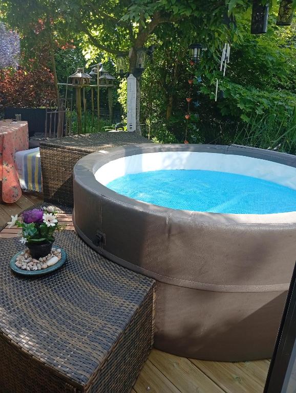 a hot tub in a backyard with a table and flowers at chambres d'hôtes naturistes de la moque souris in Saint-Pierre-de-Mailloc