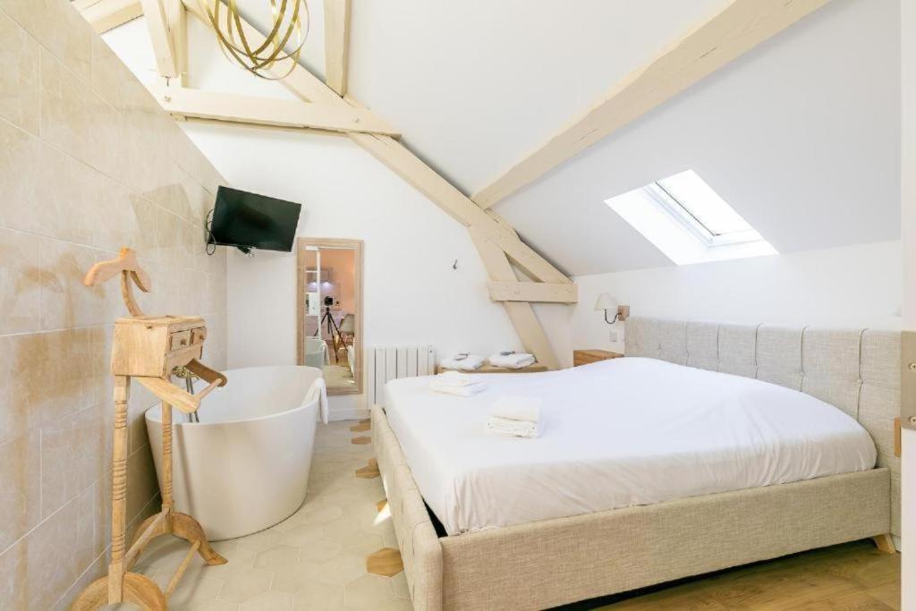 a bedroom with a white bed and a bath tub at Le Turgot - Charme et détente in Dijon
