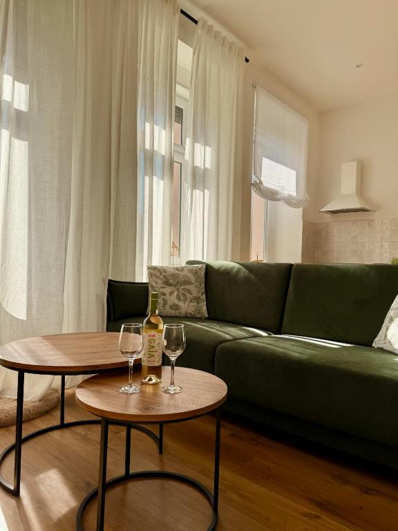 a living room with a green couch and two tables with wine glasses at Apartament Mariański in Lądek-Zdrój