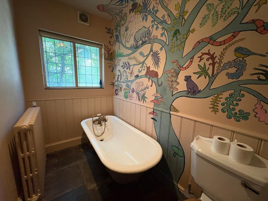 a bathroom with a tree painted on the wall at Cosy Cottage in Melbourne in Melbourne