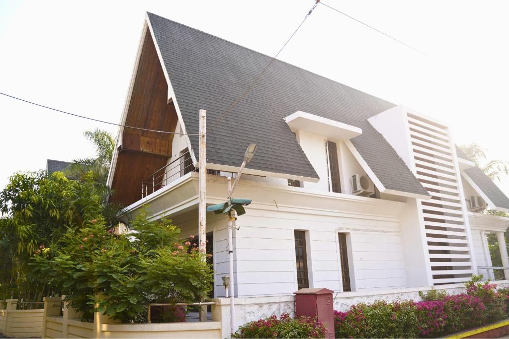ein weißes Haus mit einem schwarzen Dach in der Unterkunft Holiday Aapke Liye Bungalow no 8- 3 BHK in Khopoli
