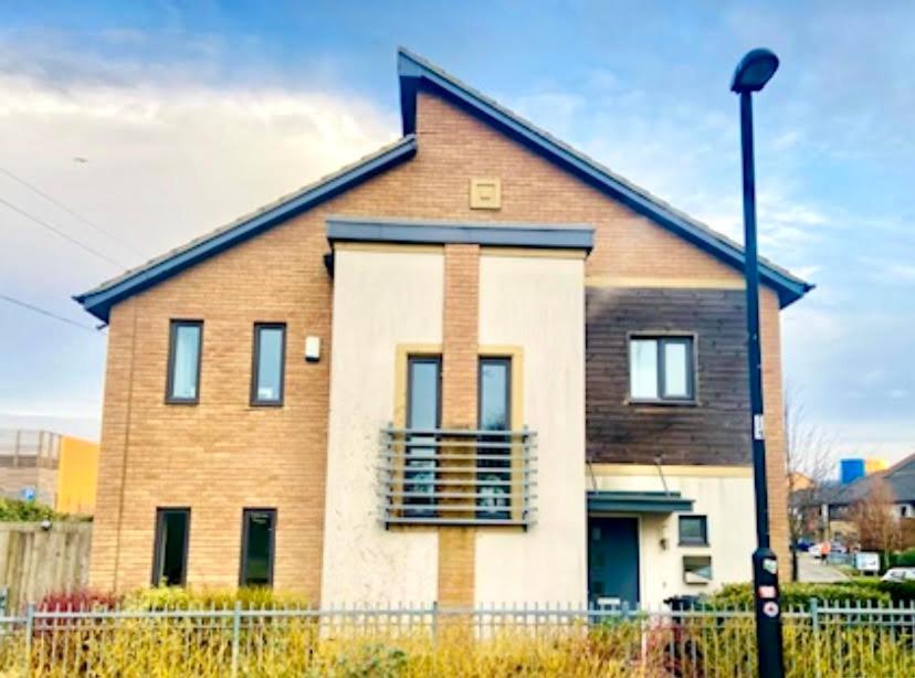 a large brick house with a fence in front of it at Hawksbill 3 Bed Detached house with private parking in Peterborough