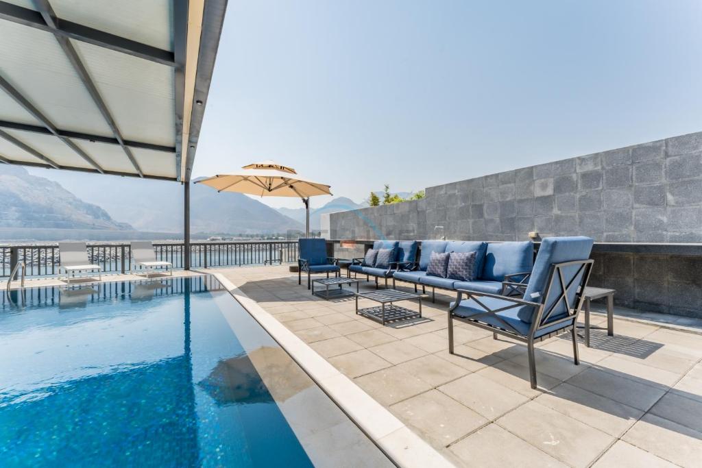 a patio with a pool and chairs and an umbrella at Sea Views 4BR and Assistant's Room Villa with Private Pool, Sharm - Al Dana Villa, Al Dana Island by Deluxe Holiday Homes in Fujairah