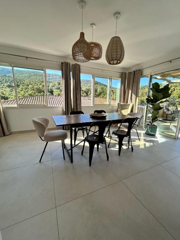 une salle à manger avec une table, des chaises et des fenêtres dans l'établissement Appartement de standing aux portes de Propriano, à Propriano